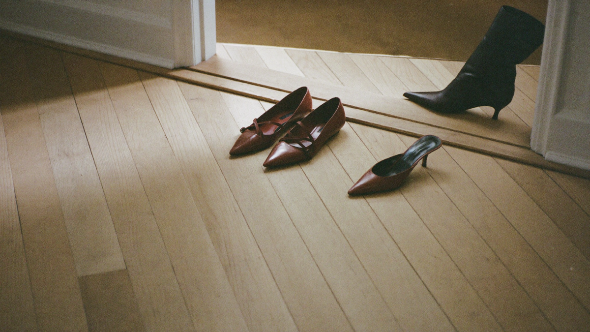 Pointed leather flats, backless mules and an ankle boot arranged on pale wide-plank floorboards