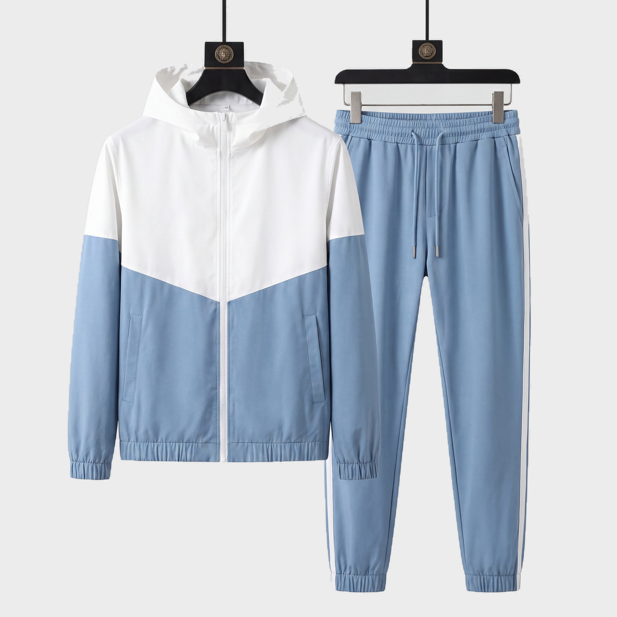 Genoa dual tone tracksuit in light blue and white, hooded jacket and joggers on black hangers against a light grey studio background