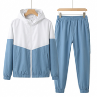 Genoa dual tone tracksuit in light blue and white, zip jacket and joggers on hangers against a white background