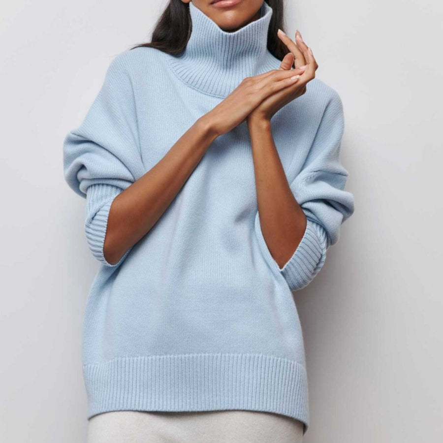 Lydia turtleneck sweater in light blue, hands resting at the high neck